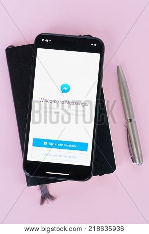 WARSAW, POLAND - DECEMBER 02, 2017: New Iphone X mobile phone with facebook messanger page on pink background