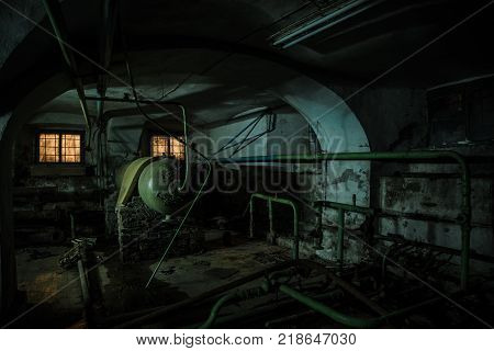 Old creepy cellar of abandoned asylum. Old rotten boiler, heating pipes.