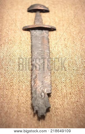War symbol. Medieval viking rusty sword on linen cloth. Selective focus