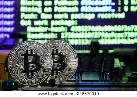 The digital process of cryptocurrency mining by using the GPUs. Bitcoins and video card on a working display and mining screen