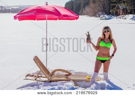 Novokuznetsk, Kemerovo region, Russia - 23 Feb, 2017 : White beaches of Siberia is an enterteiment activity where people playing beach games dressed in bikini in winter. Woman in bikini with pineapple