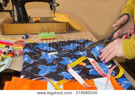Tailor Woman fashion designer working at studio. Fashion designer cutting textile next to a sewing machine