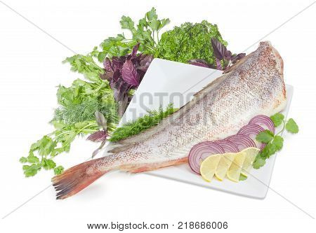 Carcass of the uncooked red cod without head sliced lemon and red onion on the large square white dish cilantro basil parsley and dill twigs on a white background