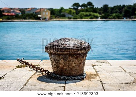 Old rusty steel mooring bollard pole on a pier. The best way for boat or ship mooring in harbor. Croatia Silba.