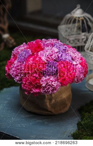 bouquet of carnations in a basket from a fabric of flax. Colorful bouquet at table.
