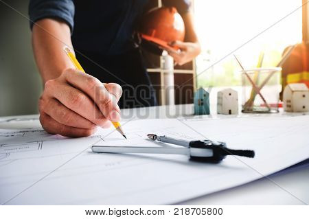 Young engineers using pencil yellow with Drawing circle drawing house building stucture before presenting it at the conference with house model and dividers in work. Architecture design concept.