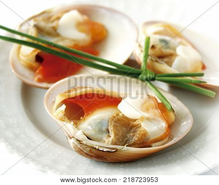 Closeup of clams on a plate, garnished with chives.