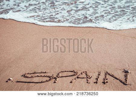 Spain written in the sand at the beach.