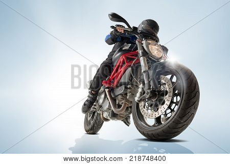 Biker in black jacket and helmet sitting on his sportive bike on blue studio background