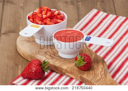 Sliced Strawberries And Strawberry Puree In Measuring Cups. Olive Tree Board