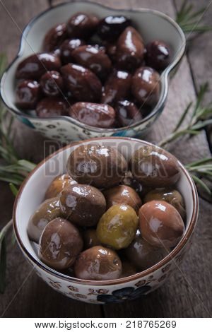Cured, pickled or brined olive fruit on wooden table