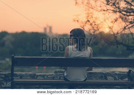 Woman sitting on a bench and watching the distant city scenery.