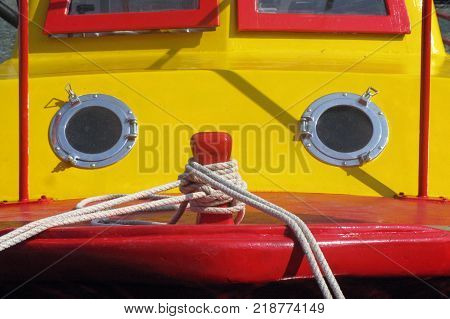 A yellow and red painted wooden fishing boat looks like a human face