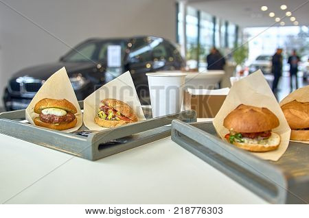 Prepare delicious burger with fried meat cutlet placed on a table in wooden tray, diagonally placed. In the showroom.