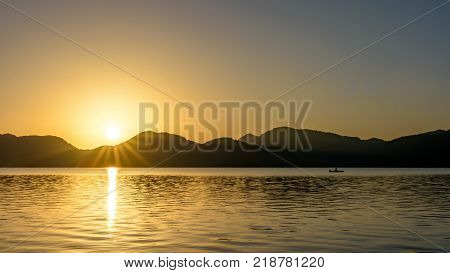 Sunrise over mountains and lake with canoeist