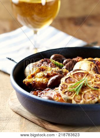 Grilled chicken pieces with olives in a pan and glass of beer