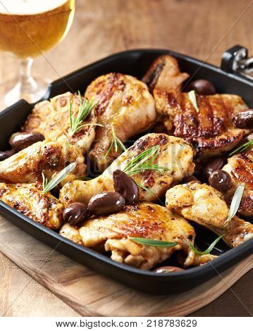 Grilled chicken pieces with olives in a pan