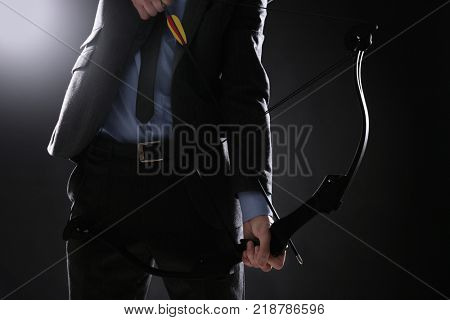 Businessman practicing archery on dark background