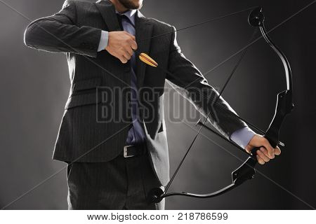 Businessman practicing archery on dark background