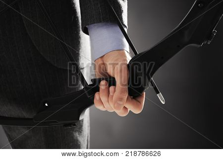 Businessman practicing archery on dark background