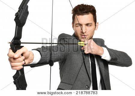 Young businessman practicing archery on white background