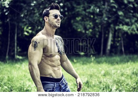 Handsome Muscular Shirtless Hunk Man Outdoor in City Park Standing on Grass. Showing Healthy Muscle Body While Looking away
