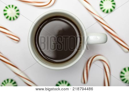 Hot chocolate or coffee against a white background with candy canes and mints