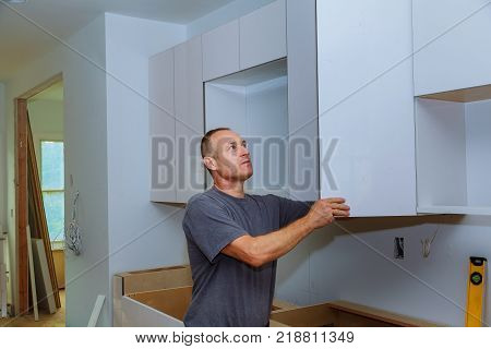 Closeup of a cabinet installer installing hardware on new kitchen cabinets. Installing new kitchen