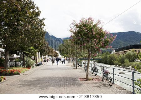 Italian People And Foreigner Travelers Stop Bicycle And Walking On The Footpath At Riverside Of Pass
