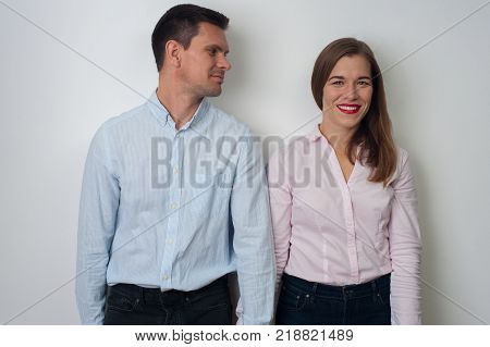 Portrait of middle aged couple holding their hands. Positive attractive man smiling and looking at a cute young woman in casual clothes on white background