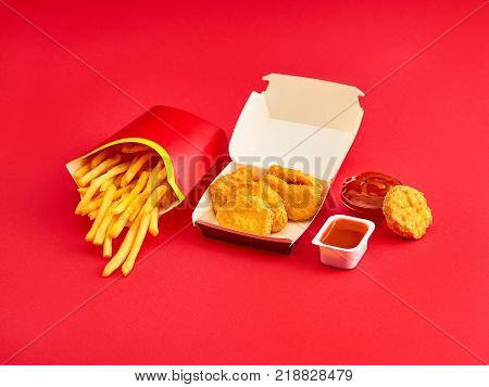 The chicken nuggets and french fries on red background