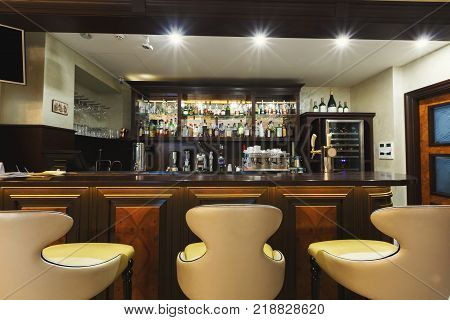 Hotel lounge bar with bottle shelves and seats. Barroom in restaurant, ready for work, copy space. Cafe background