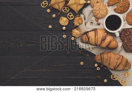 French croissants and coffee background. Tasty french breakfast with variety of homemade cookies, nuts and buns. Mockup for sweet pasrty recipe, top view, copy space