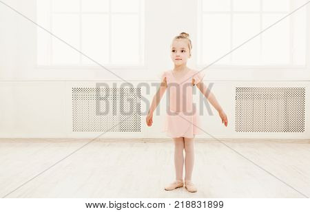 Little ballerina exercising in ballet costume, standing on her toes. Cute small ballerina training classical dance exercisese