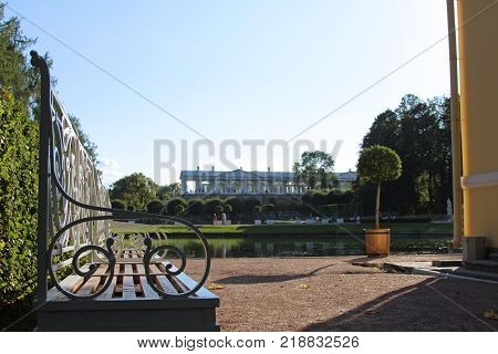 Classical baroque bench in the green garden and summer sunny lake in the Catherine park, Pushkin, St. Petersburg