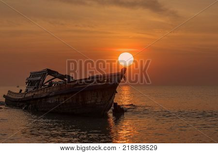 Old boat on the beach at sunrise.