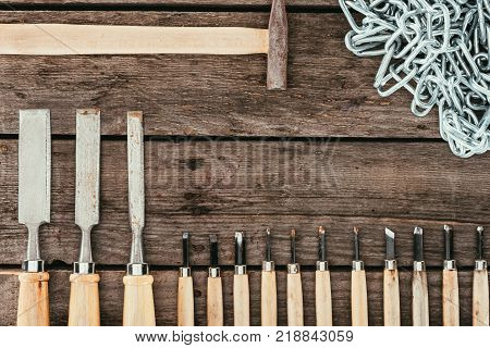 flat lay with chain, hammer and chisels for woodcraft on dark wooden tabletop