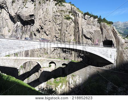St. Gotthard and Teufelsbruecke, alpine Devil's road bridge and tunnel over Reuss river near Andermatt town in Switzerland, rocky mountains landscape scenery in 2017 warm summer day, Europe on July.