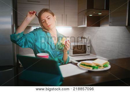 Busy woman eating, drinking coffee, talking on the phone, working on tablet at the same time. Businesswoman doing multiple tasks. Multitasking business person. Freelancer works at night.