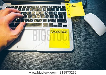 hand on laptop with yellow sticker with deadline text on it