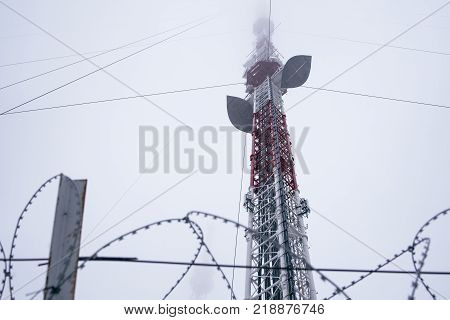 Television tower in the fog on a background cloudy sky