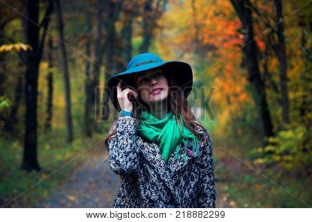 Pretty romantic girl in autumn clothes walks in a park. The mood of autumn, leaf fall. Autumn fashion.
