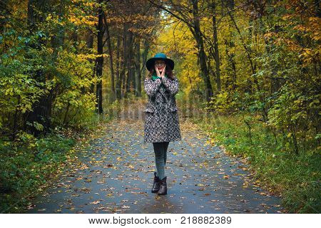 Pretty romantic girl in autumn clothes walks in a park. The mood of autumn, leaf fall. Autumn fashion.