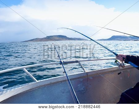 Fishing boat with fishing rods floating in open sea. Background beautiful sky. Sport sea fishing
