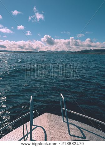 Fishing boat with fishing rods floating in open sea. Background beautiful sky. Sport sea fishing