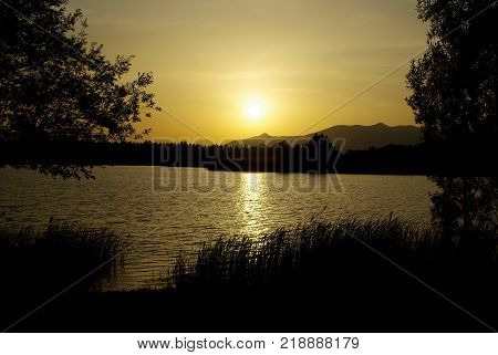 sun slowly sets on the lake and reflects its light on the water