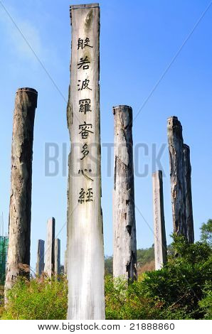 Percorso di saggezza del Sutra del cuore - preghiera cinese su tronchi sotto un cielo blu da Parco del paese di Lantau Island