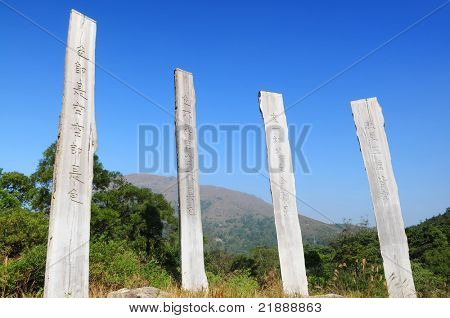 Percorso di saggezza del Sutra del cuore - preghiera cinese su tronchi sotto un cielo blu da Parco del paese di Lantau Island
