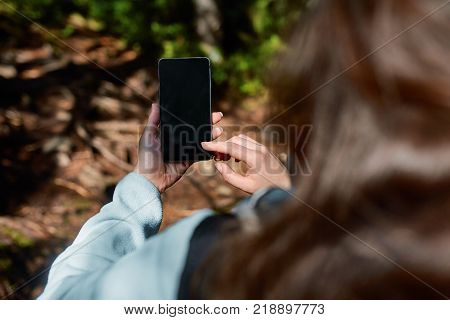 Girl Hand holding blank screen mobile phone in rain forest garden and cross process and soft flare filter