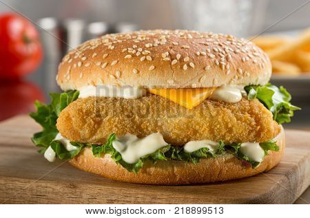 A delicious crispy fish burger with cheese lettuce and mayonnaise.